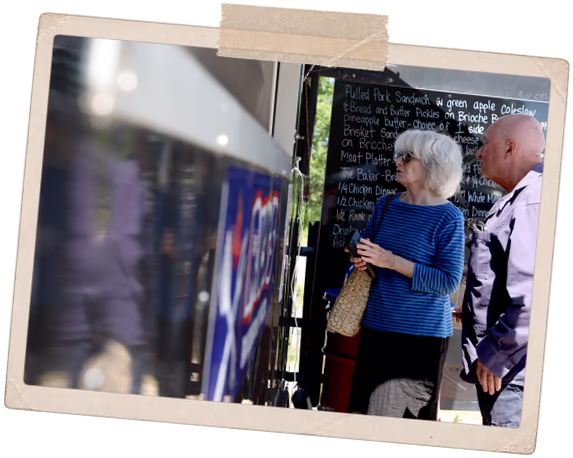 Two customers reading the chalkboard menu beside the truck